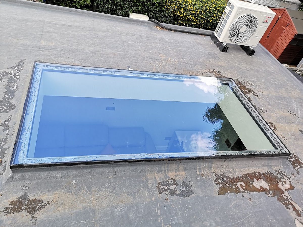 A flat-roof skylight cleaned to a clear sparkle by AE Exterior Cleaning, reflecting a blue sky.
